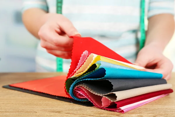 Colorful fabric samples in female hands on light blurred background — Stock Photo, Image