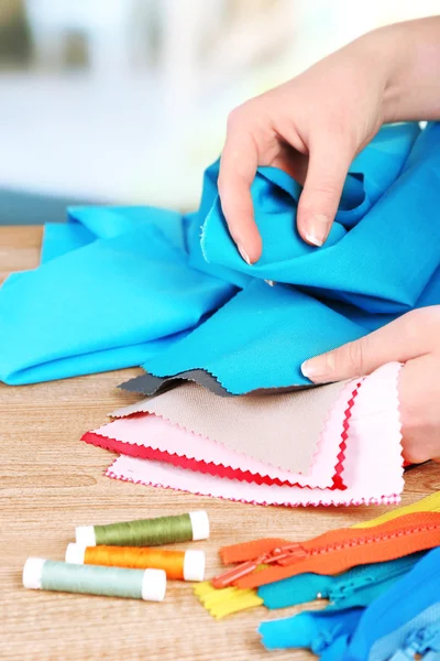 Échantillons de tissu coloré dans les mains féminines sur fond flou clair — Photo