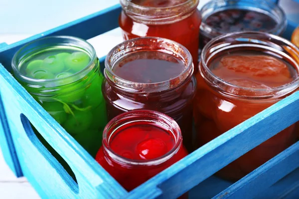 Tarros caseros de mermelada de frutas en cajón sobre fondo de mesa de madera de color — Foto de Stock