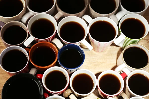 Багато чашок кави на дерев'яному фоні столу, вид крупним планом — стокове фото