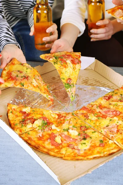 Friends hands with bottles of beer and pizza, close up — Stock Photo, Image