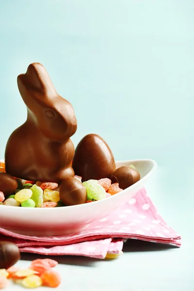 Œufs de Pâques en chocolat et lapin sur assiette, sur fond de bois de couleur — Photo