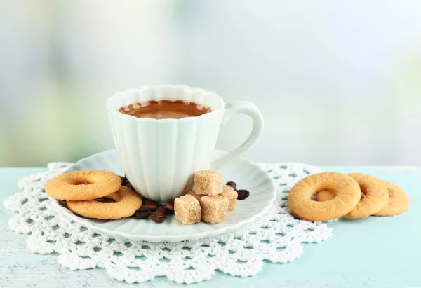 Copa de café y galletas sabrosas en la mesa de madera de color, sobre fondo claro — Foto de Stock