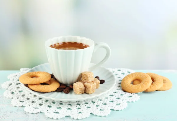 Cup of coffee and tasty cookies on color wooden table, on light background — Stock Photo, Image