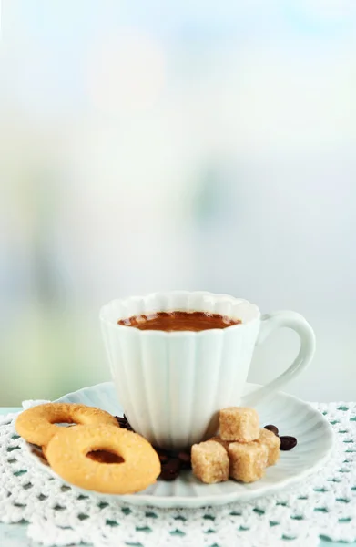 Xícara de café e biscoitos saborosos na mesa de madeira a cores, no fundo claro — Fotografia de Stock