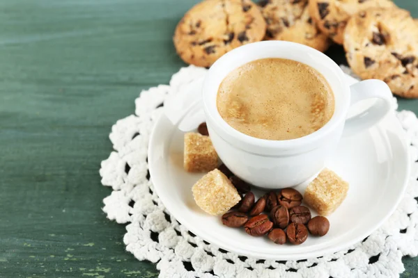 Cup of coffee and tasty cookie on color wooden background — Stock Photo, Image