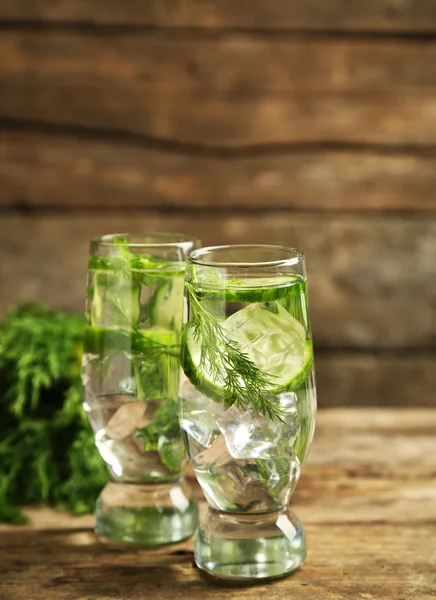 Glasögon med färsk ekologisk gurka vatten på träbord — Stockfoto
