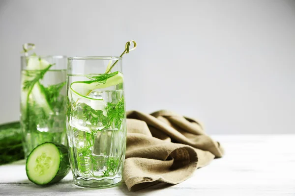 Óculos com água fresca de pepino orgânico sobre mesa de madeira, sobre fundo cinzento — Fotografia de Stock