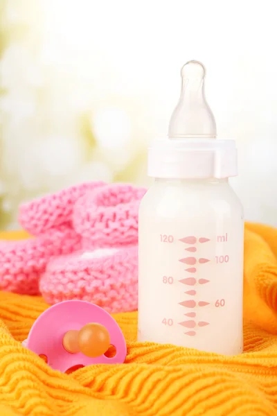 Milk bottle, pacifier and bootees — Stock Photo, Image