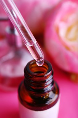 Damlalık şişe parfüm pembe bir arka plan üzerinde Şakayık ile