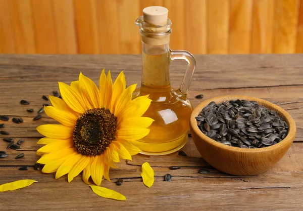 Sunflower with seeds and oil on wooden background — Stock Photo, Image
