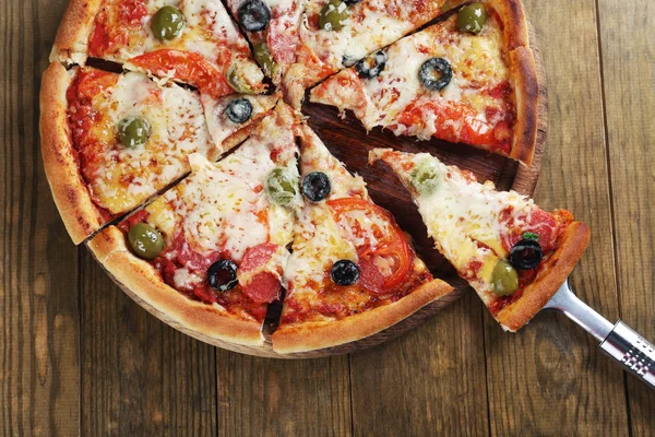 Pizza com queijo e remo de pizza em fundo de mesa de madeira — Fotografia de Stock