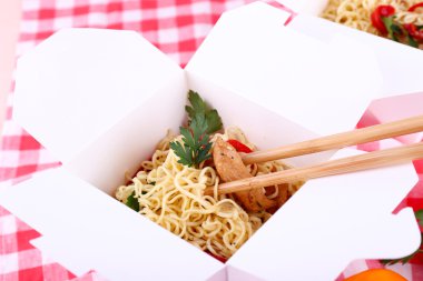 Çin eriştesi ve paket servisi olan restoran kutusunda kumaş arka plan üzerinde sopa