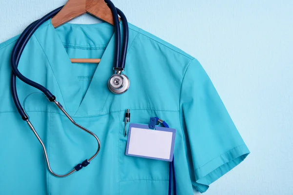 Camisa médica con estetoscopio en percha sobre fondo azul — Foto de Stock