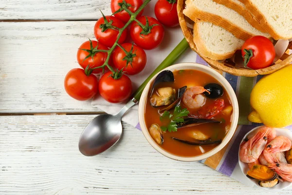 Tasty soup with shrimps, mussels, tomatoes and black olives in bowl on wooden background — Stock Photo, Image