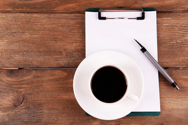 Taza de café en platillo con hoja de papel y pluma sobre fondo de mesa de madera —  Fotos de Stock