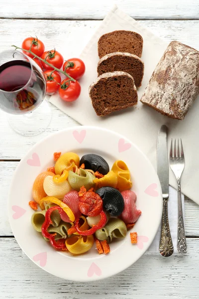 Massa multicolorida saborosa com pimenta, cenoura e tomate sobre fundo de mesa de madeira — Fotografia de Stock