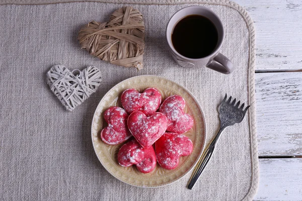 Cookies in vorm van hart op plaat met kop koffie op servet en kleur houten planken achtergrond — Stockfoto