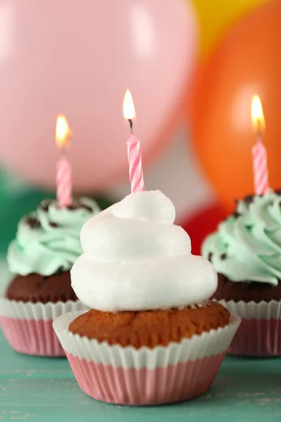 Deliciosos cupcakes de aniversário na mesa em fundo brilhante — Fotografia de Stock