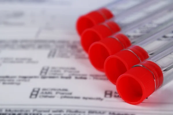 Test tubes with medical history form close up — Stock Photo, Image