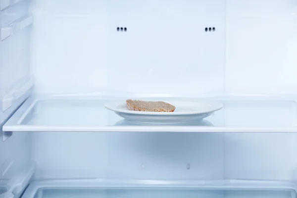 Piece of bread on plate in refrigerator — Stock Photo, Image