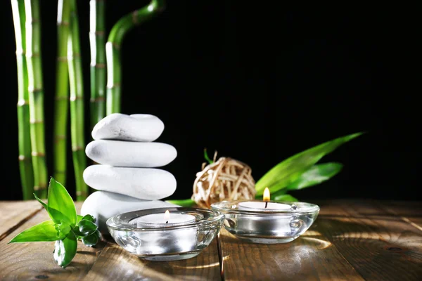 Beautiful composition with spa stones and candles on table on dark background — Stock Photo, Image