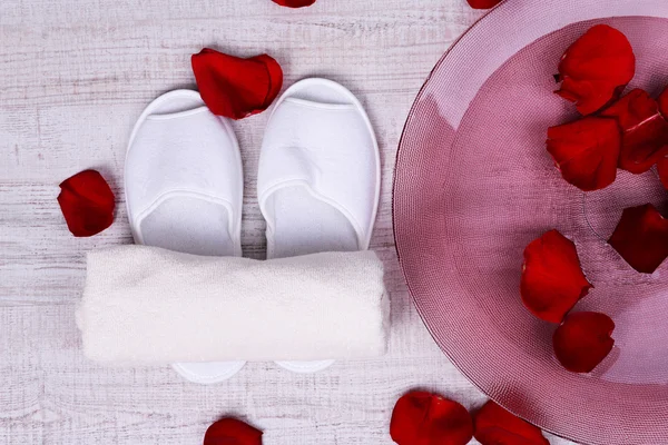Spa 碗水、 玫瑰花瓣、 毛巾和拖鞋在明亮的背景上。修脚或天然温泉治疗的概念 — 图库照片