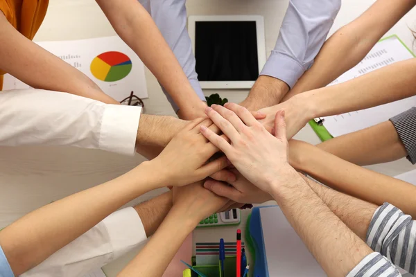 Verenigd handen van zakelijke team op werkruimte achtergrond bovenaanzicht — Stockfoto