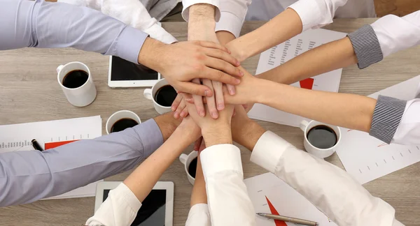 Mãos unidas da equipe de negócios no fundo do espaço de trabalho vista superior — Fotografia de Stock