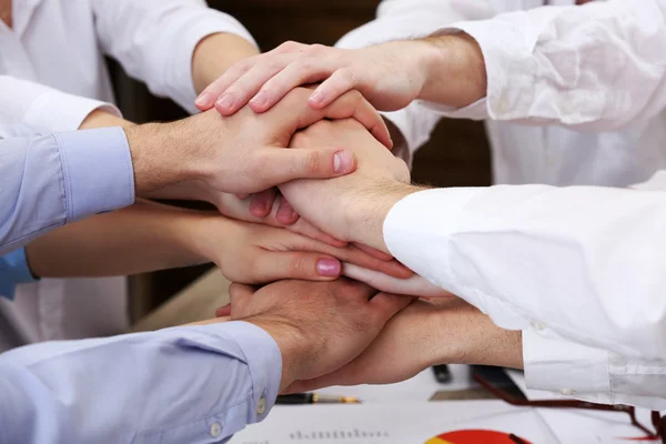 Mani unite del team aziendale sullo sfondo dello spazio di lavoro — Foto Stock