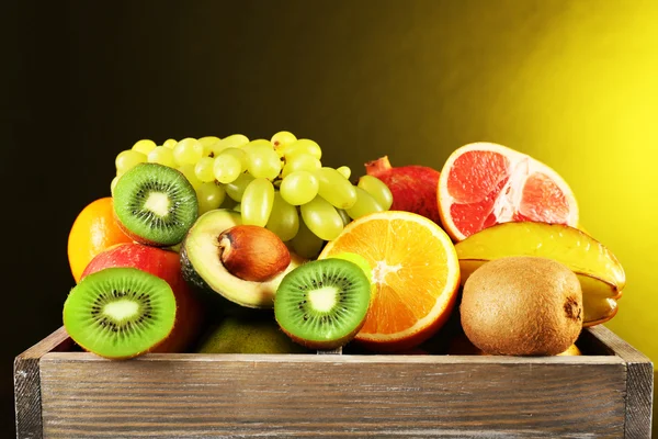 Berbagai macam buah dalam kotak pada latar belakang kuning gelap — Stok Foto