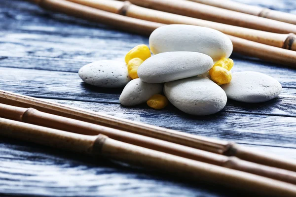 Spa stones with dry bamboo on wooden background — Stock Photo, Image