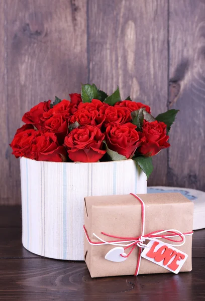 束红玫瑰纺织盒，木制背景的礼物 — 图库照片