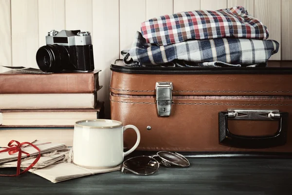 Vintage suitcase with clothes and books on wooden background — Stock Photo, Image