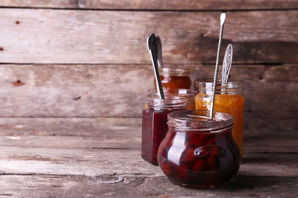 Frascos de sabrosa mermelada sobre fondo de madera — Foto de Stock