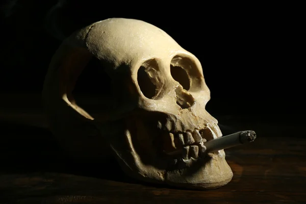 Fumar scull humano com cigarro em sua boca no fundo escuro — Fotografia de Stock