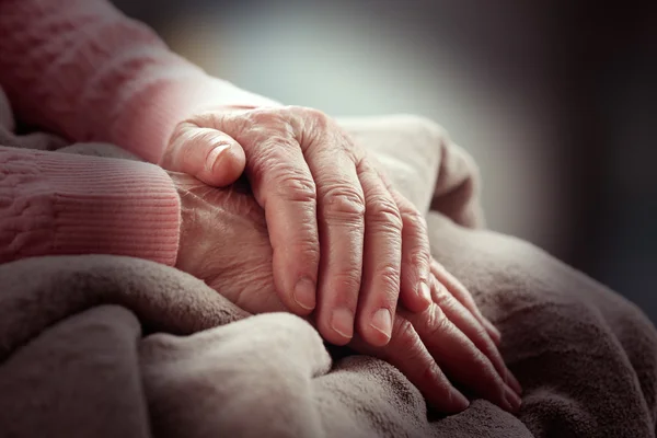 Old and young holding hands on light background, closeup — Stock Photo, Image