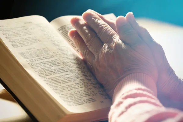 Kezét a régi nő Biblia asztalon, közelkép — Stock Fotó
