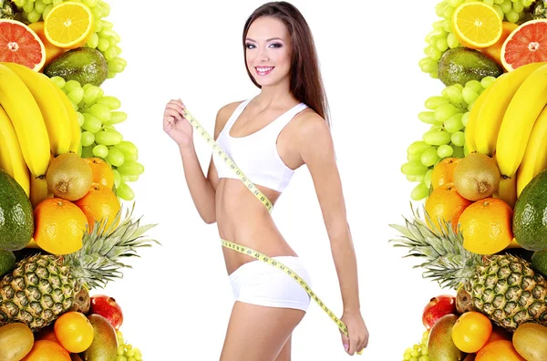 Mulher bonita que mede seu corpo com fita isolante em branco no quadro de frutas tropicais — Fotografia de Stock