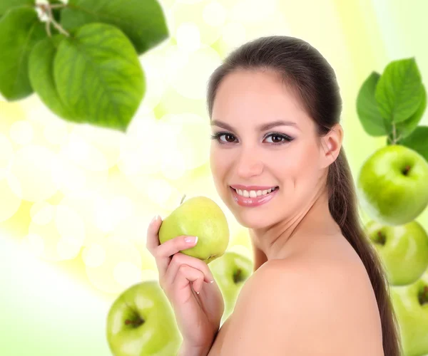 Beautiful young woman with green apple on natural background — Stock Photo, Image