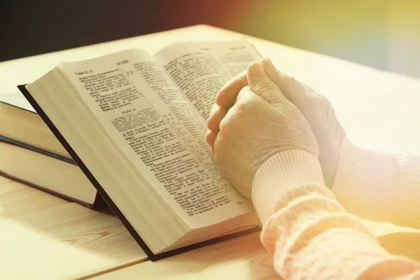 Mani di vecchia donna con Bibbia sul tavolo — Foto Stock