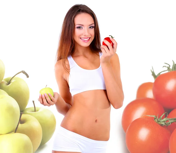 Beautiful young woman with apple and tomato in hands isolated on white, tomatoes and apples around — Stock Photo, Image