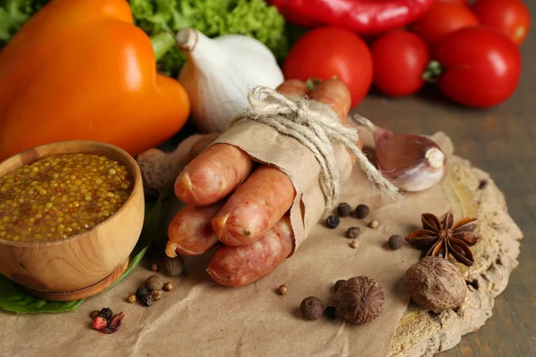 Samenstelling van dunne worst, mosterd in kom en specerijen op houten achtergrond — Stockfoto