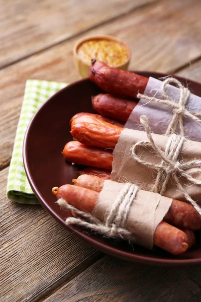 Assortiment de saucisses fines et d'épices sur assiette, sur fond de bois — Photo