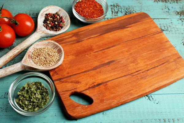 Different spices and herbs with cutting board on color wooden table background — Stock Photo, Image