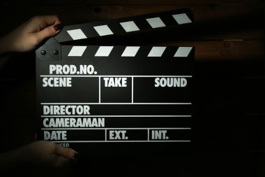 Koyu renk arka plan üzerinde kadın elinde film tokmağı