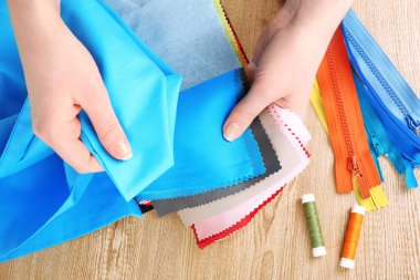 Eller ahşap masa arka plan üzerinde renkli kumaş örnekleri