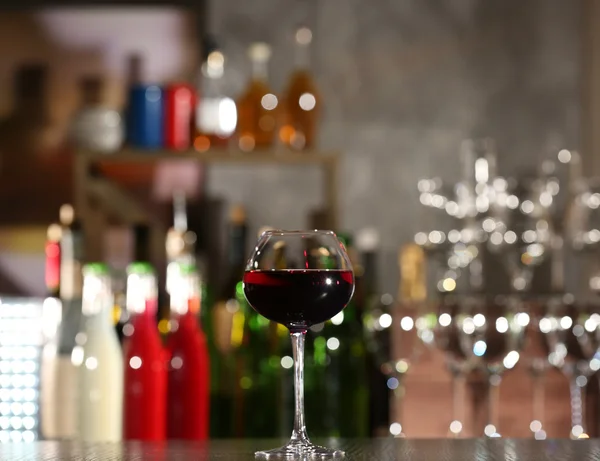 Glass of red wine with bar on background — Stock Photo, Image