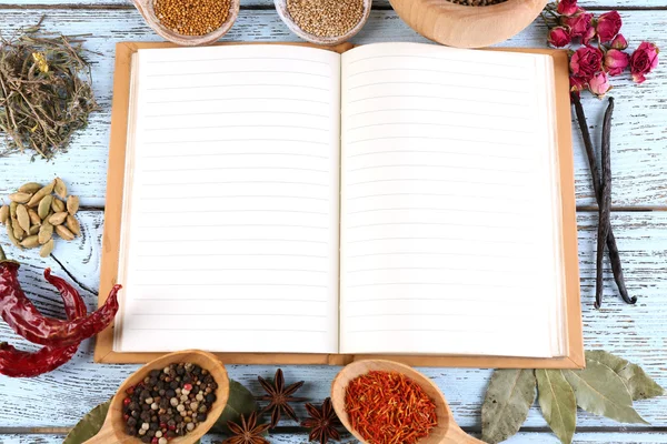 Especias con libro de recetas sobre fondo de mesa de madera de color — Foto de Stock