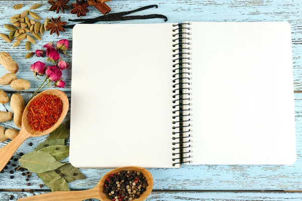 Specerijen met recept boek op kleur houten tafel achtergrond — Stockfoto